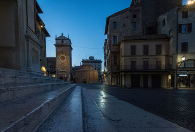 Empty road amidst buildings in city at dusk