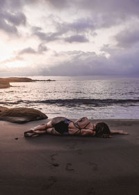 Rear view of woman lying on beach against sky