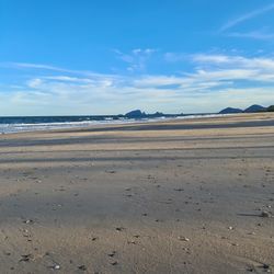 Scenic view of beach against blue sky