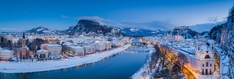 Panoramic shot of buildings by mountain against sky during winter