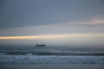 Boat sailing in sea at sunset