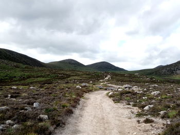 Dirt road along landscape against sky