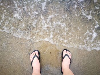 Low section of man standing at beach