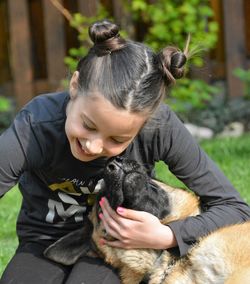 Cheerful girl plying with dog on sunny day