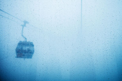Overhead cable car seen through wet glass window during monsoon