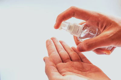 Close-up of hand holding bottle against white background