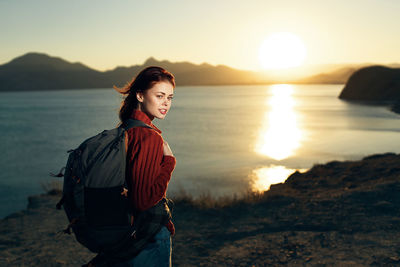 Woman standing on beach against sky during sunset