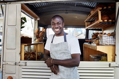 Portrait of smiling mid adult male owner standing outside food truck