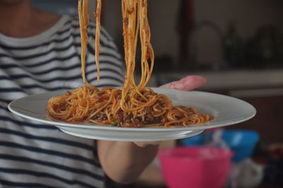 Midsection of person holding spaghetti in plate