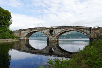 Arch bridge over river against sky