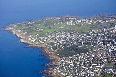 Aerial view of town by sea against blue sky