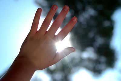 Low angle view of human hand against bright sun