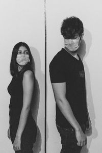 Portrait of young woman standing against wall