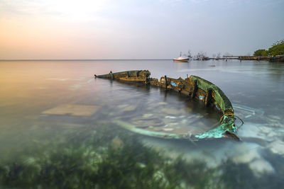 High angle view of shipwreck in sea against sky during sunset