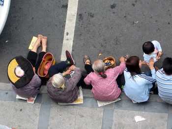 High angle view of family sitting on sidewalk in city