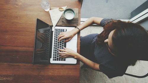 High angle view of businesswoman using laptop while sitting at table in office