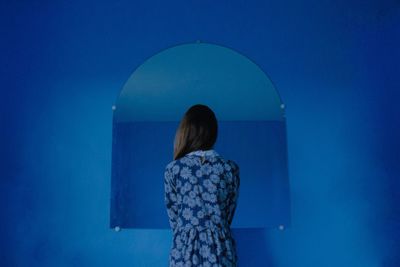 Rear view of woman standing against blue sky