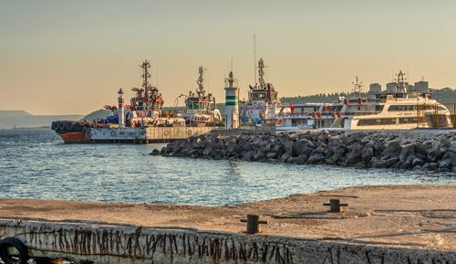 Pier at harbor against sky during sunset