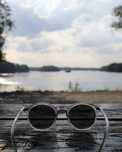 Close-up of sunglasses on lake against sky