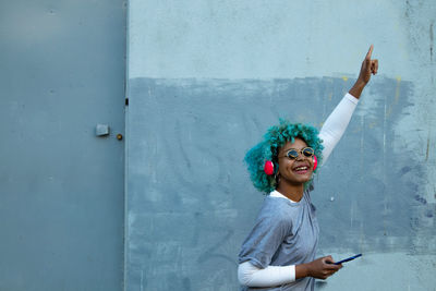 Afro american woman dancing in the street smiling with phone and headphones