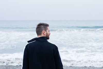 Rear view of man looking at sea against sky