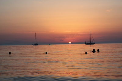 Silhouette sailboat sailing on sea against sky during sunset