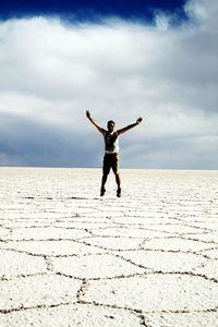 Full length of man with arms outstretched at salar de uyuni against sky