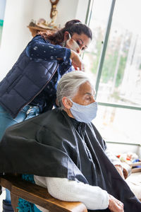 Beautician treating hair of customer at home