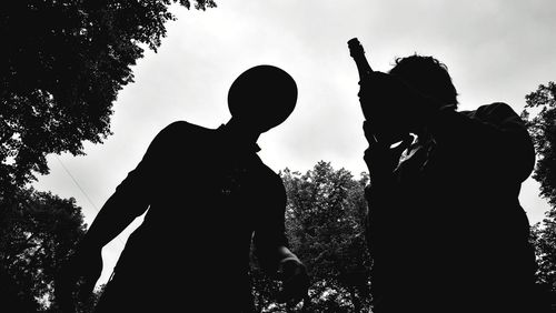 Low angle view of silhouette man against trees against sky