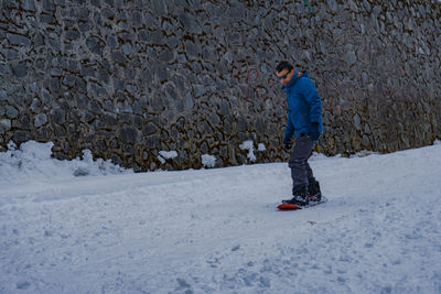 Full length of man snowboarding on snow covered land