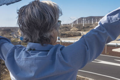 Rear view of woman standing against sky in city