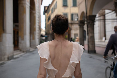 Rear view of woman walking on street against buildings in city