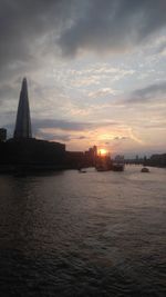 Sea by buildings against sky during sunset