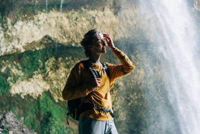 Portrait of an active woman hiker with a backpack in a mountain canyon near a large waterfall.