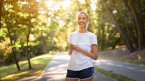 Portrait of smiling young woman standing against trees