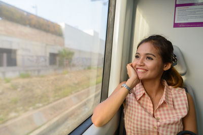 Portrait of a smiling young woman standing by window