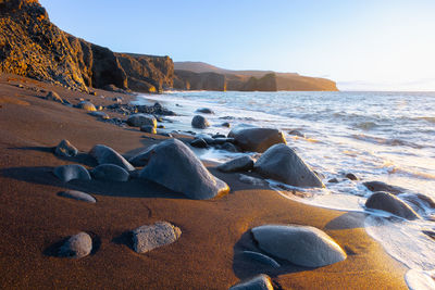 Rocks on beach against clear sky