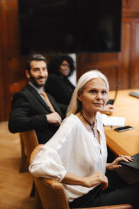 Multiracial female and male colleagues sitting at conference table in board room during meeting