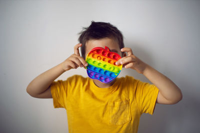 Boy in a yellow t-shirt plays a fashion game pop it in the form of a silicone apple