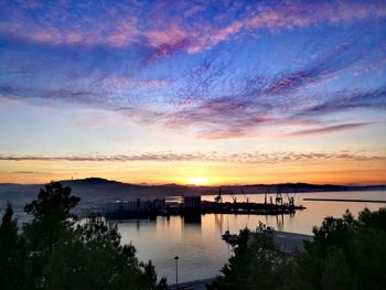 Silhouette bridge over river against sky during sunset