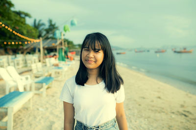 Portrait of girl standing on beach against sky