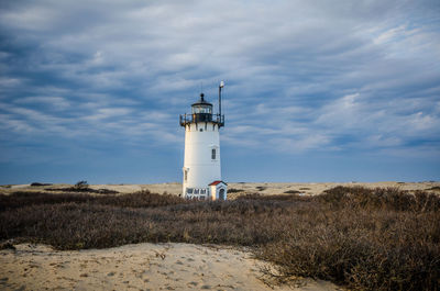 Lighthouse by street light against sky