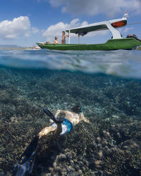 Young man snorkeling near the boat in ocean, underwater view
