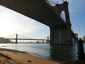 Low angle view of suspension bridges over east river against sky