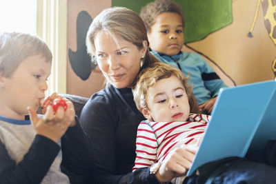 Female teacher telling story to children in kindergarten