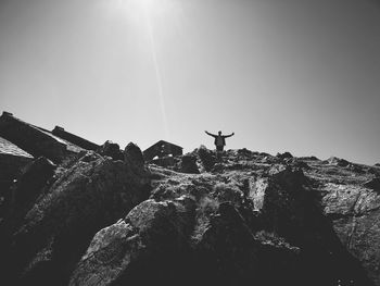 Low angle view of person on rock against sky