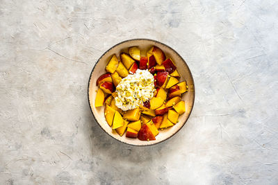Healthy fruit salad with nectarine, ricotta cream with pistachios and honey, top view. copy space