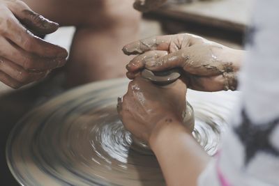 Cropped image of people working on pottery wheel