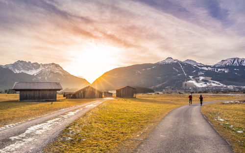 People on mountain road against sky during sunset