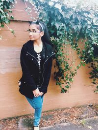 Teenage girl looking away while standing against wall